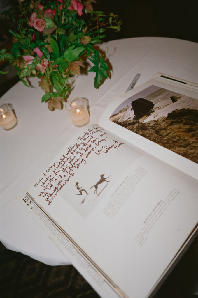 Color 35mm film photo of the wedding guestbook with handwritten notes beside a floral table arrangement at Winnetu Oceanside Resort in Martha’s Vineyard.