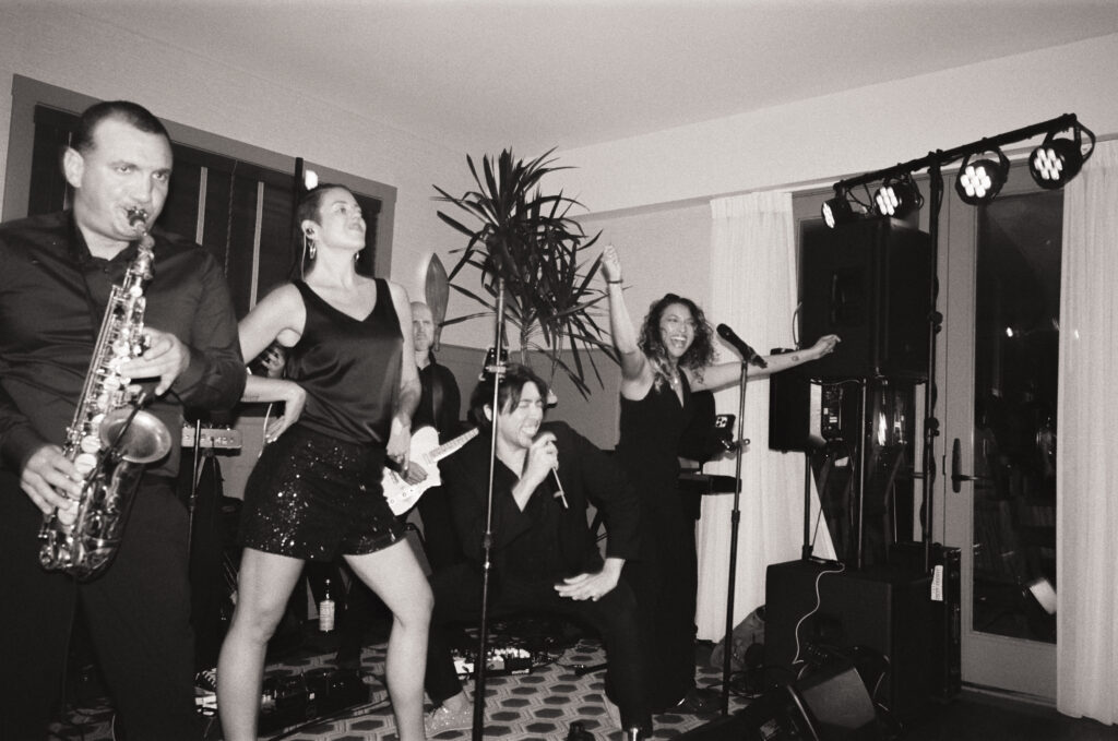 Black and white 35mm film flash photo of the live wedding band performing mid-song at a Martha’s Vineyard wedding, a candid journalistic moment full of energy.