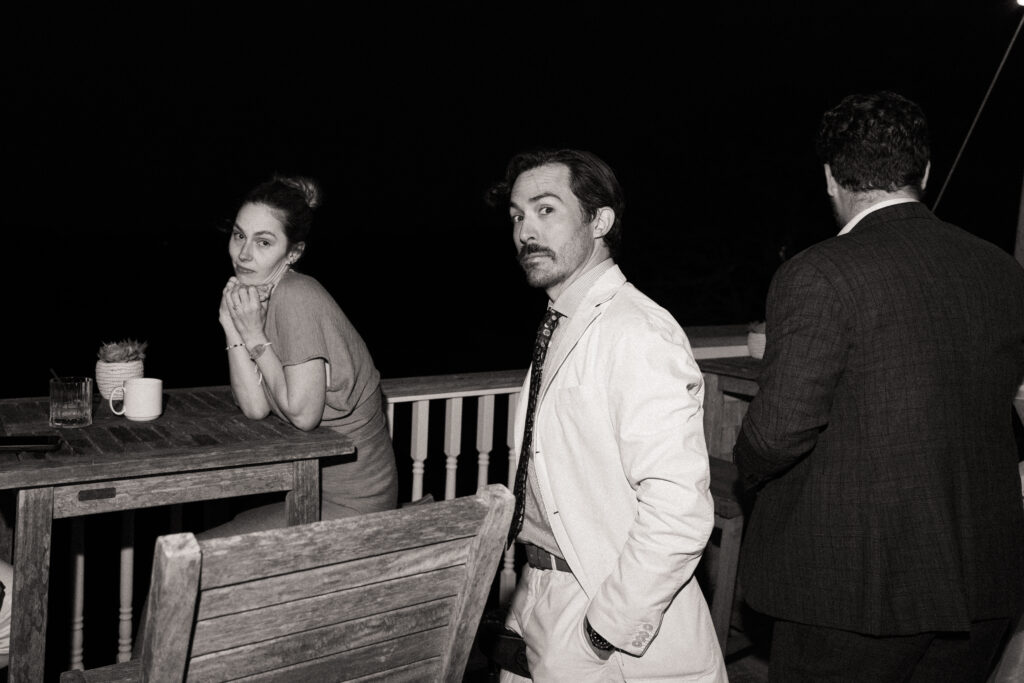 black and white candid photo of stylish guests relaxing outside during the evening reception.