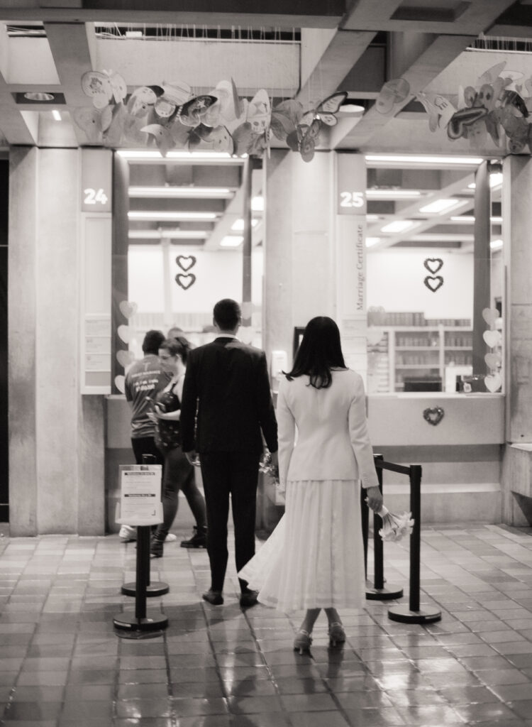 Bride and groom wait in line at their Boston City Hall elopement shot on 35mm black and white film. 