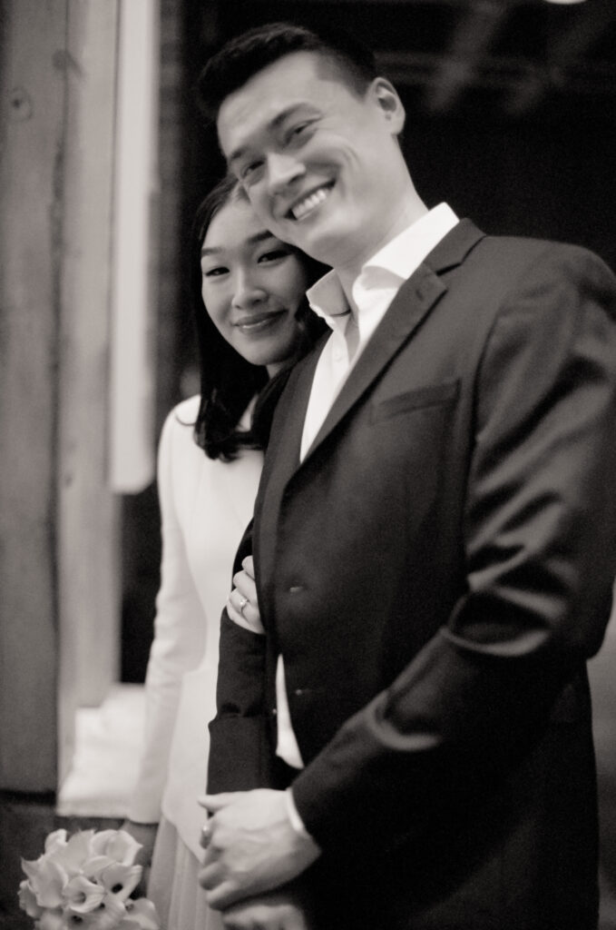 Bride and groom smile at the camera before beginning their elopement at Boston City Hall.
