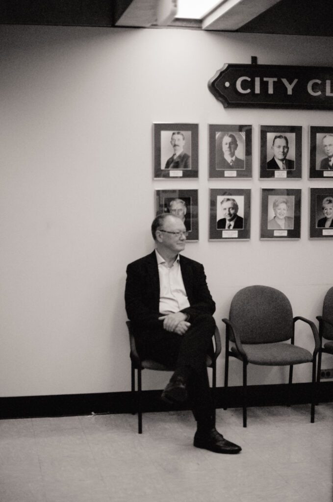 The groom's father sits in the City Hall - candid black and white film photo