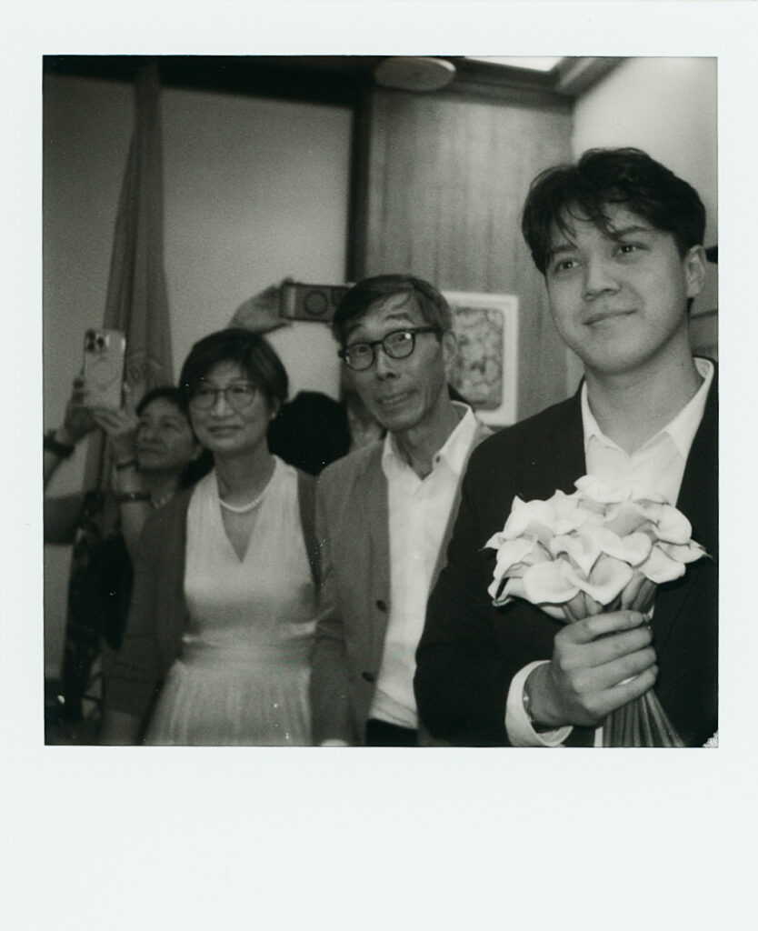 The bridge and groom's family watches their Boston City Hall elopement ceremony, wedding Polaroid black and white. 