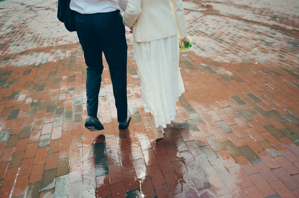 Candid of bride and grooms feet stepping on rained-on bricks at Government Center in Boston, 35mm.