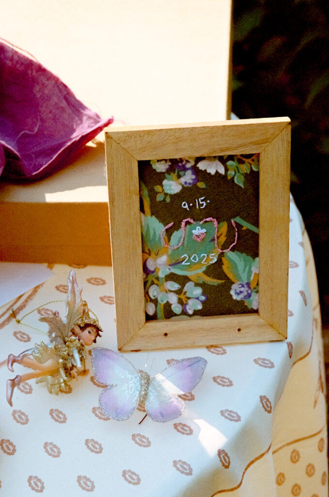 A detail photograph of an assortment of personal relationship memorabilia, highlighting a frame of an embroidered anniversary date.