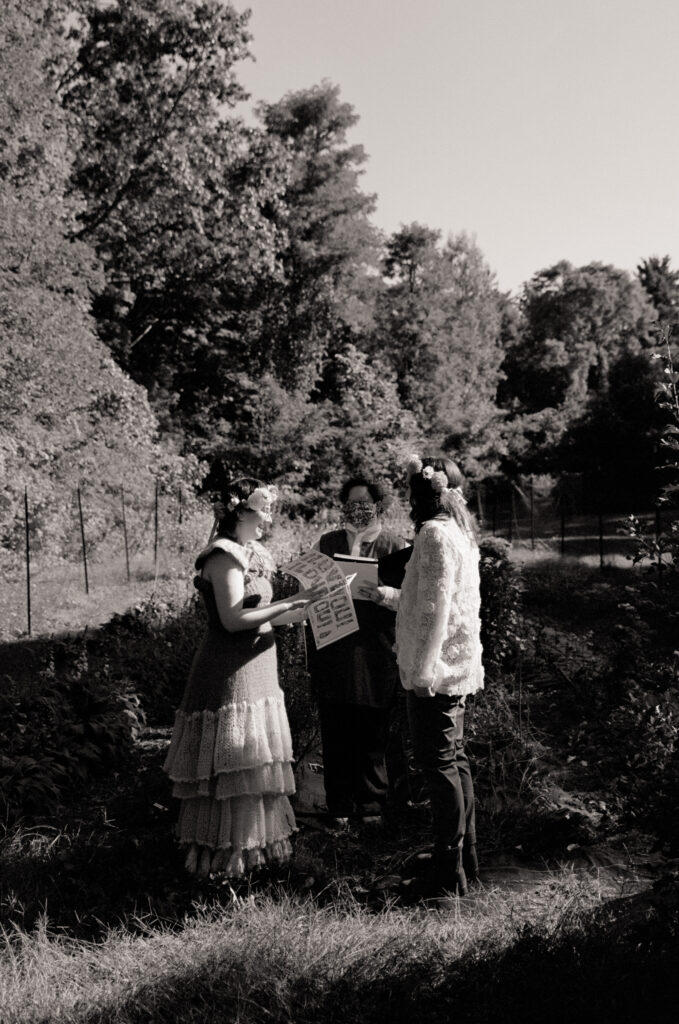 A wide angle shot of brides at their wedding alter reading a picture book, as the officiant stands behind them. 