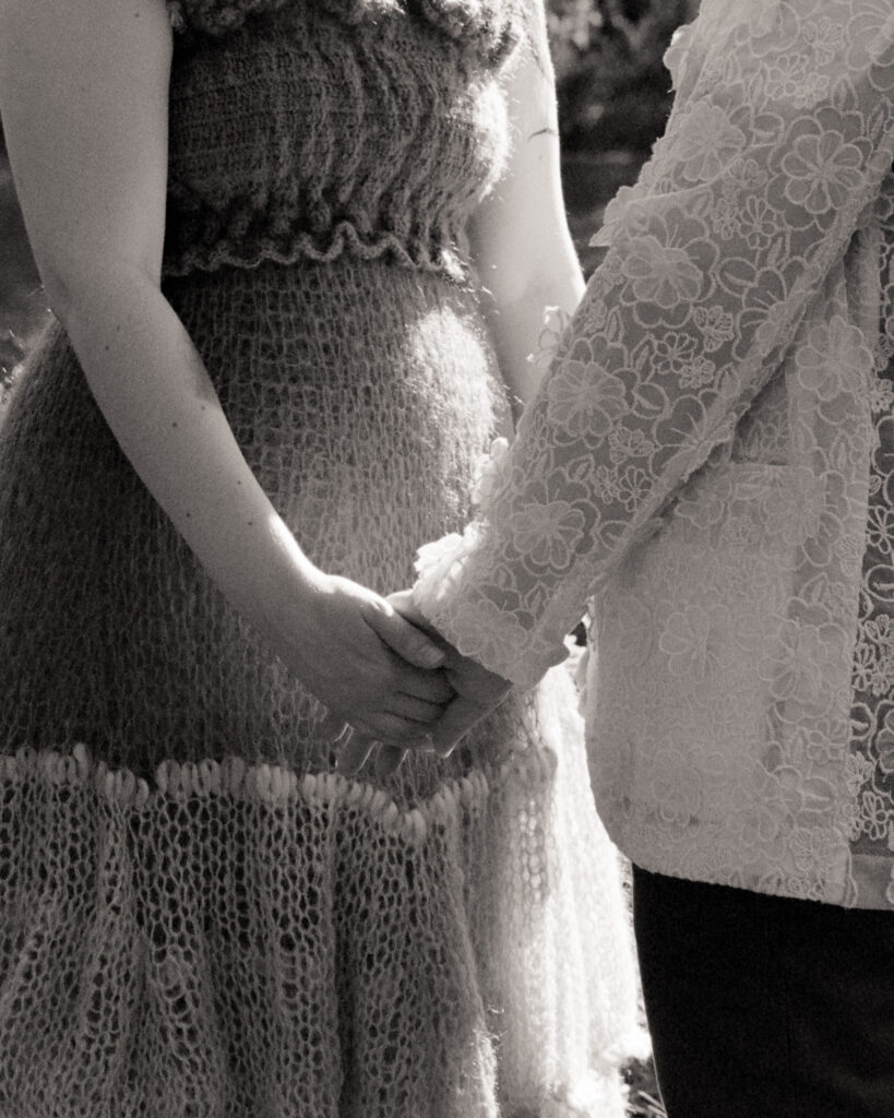Black and white documentary 35mm photograph focused on a couple holding hands. 