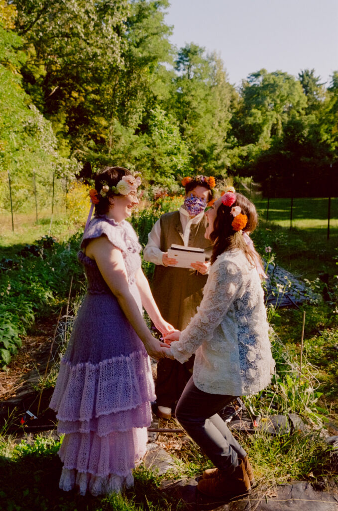 Wedding couple rejoices in celebration of completing their wedding ceremony amongst a flower field. 