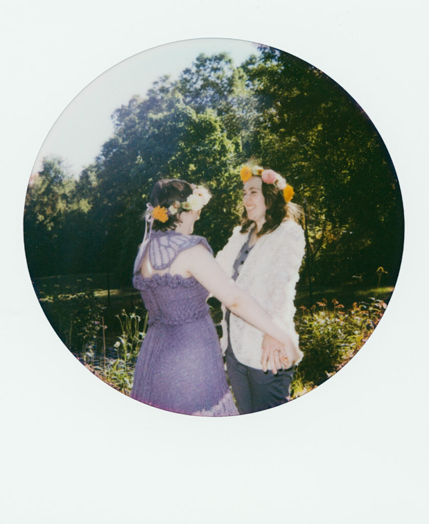 Polaroid photograph of a couple grasping hands and looking at each other with smiles after the completion of their wedding ceremony.