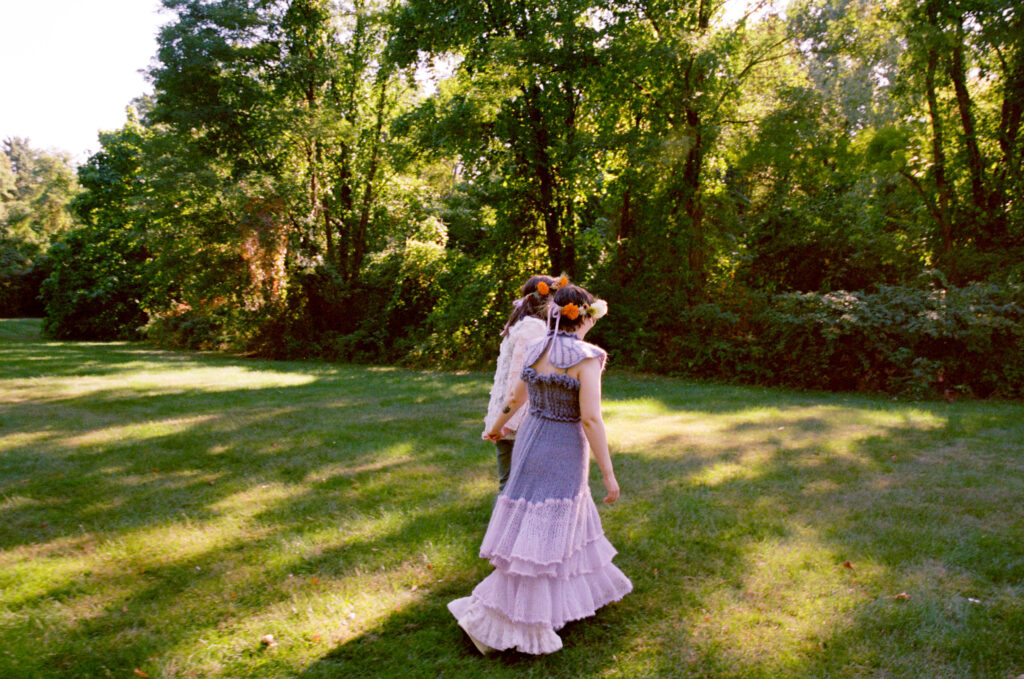 Wide angle photograph of a couple strolling through a field after completing their wedding ceremony. 