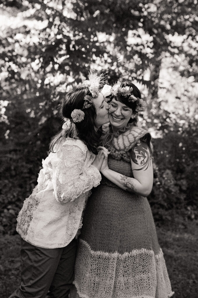 Black and white couples portrait of partner kissing the others cheek.