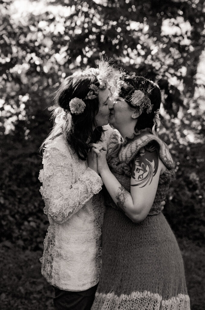 Black and white couples portrait of LGBT couple kissing on the day of their wedding