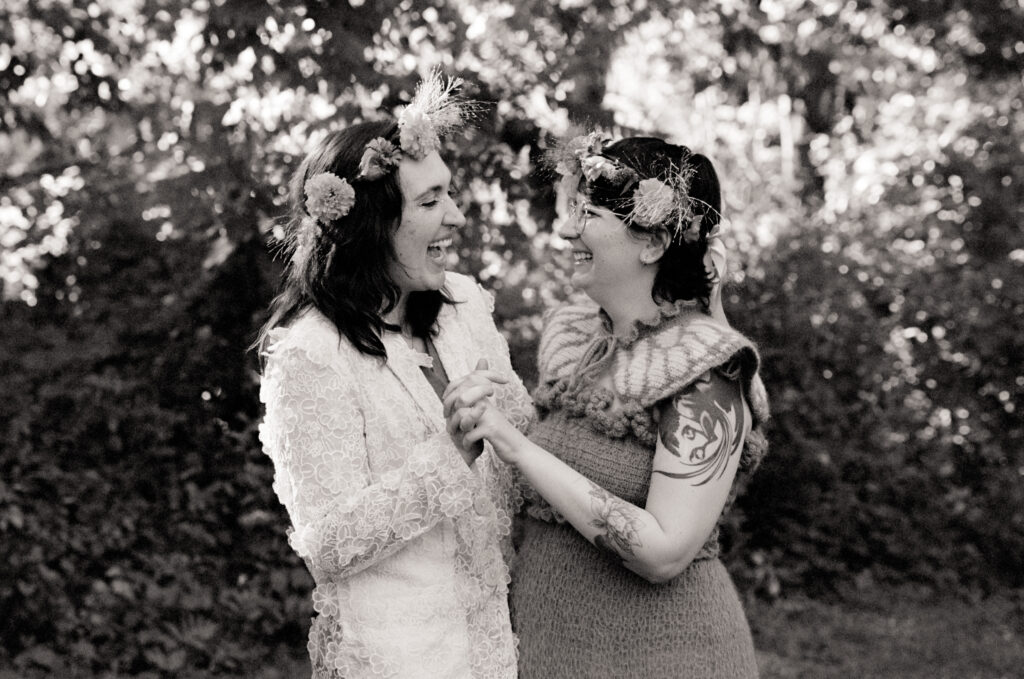Black and white photograph of a couple holding hands and staring at each other with bright smiles on their elopement day.