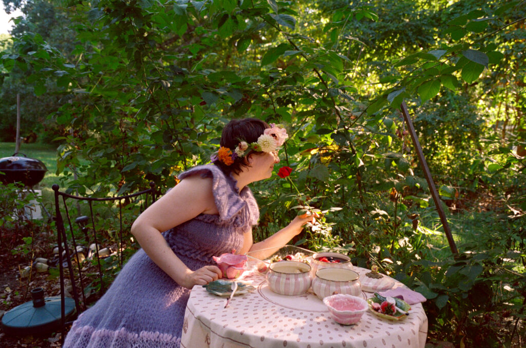 Bride leans over to smell a rose during their wedding day meal. 