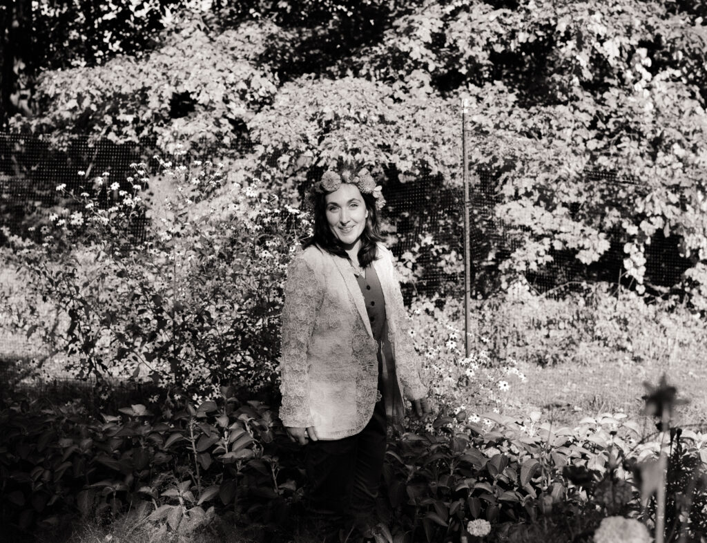 Portrait of person in suit and flower crown roaming through flowers on their wedding day.