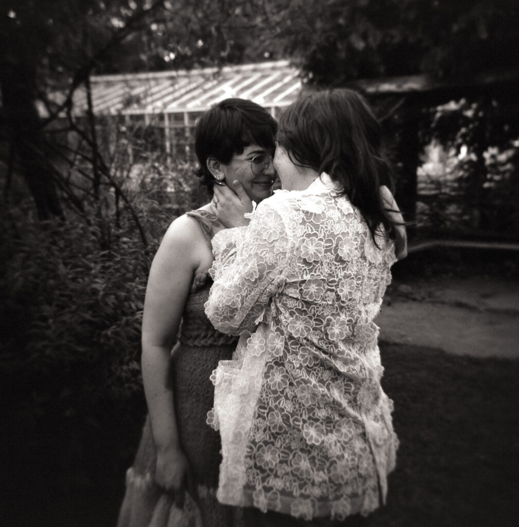Black and white photograph of candid moment between newlyweds, as one holds the others cheek.