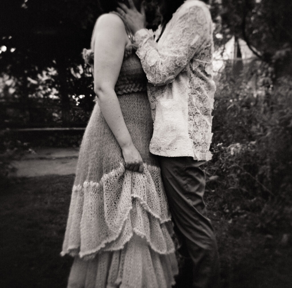 Black and white photography focusing on newlywed couples gesture, as one grips their dress and the other holds their cheek.