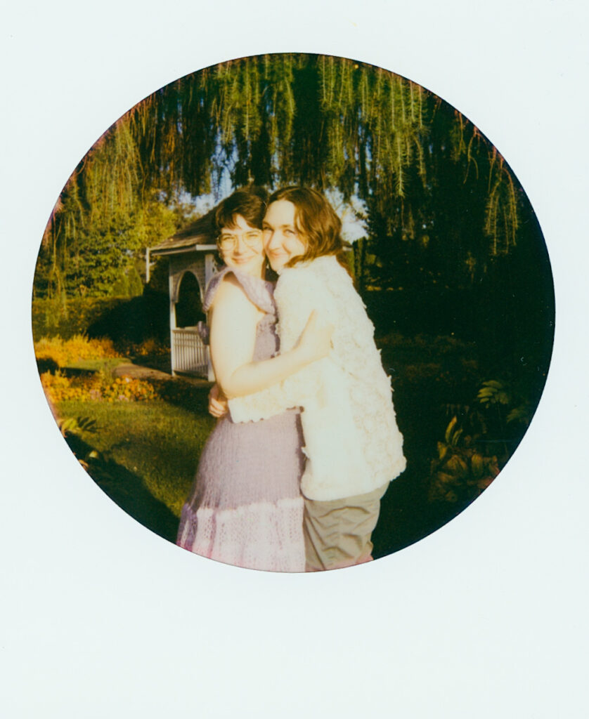 Couple holds each other tight and looks forward as they are outlined by vines.