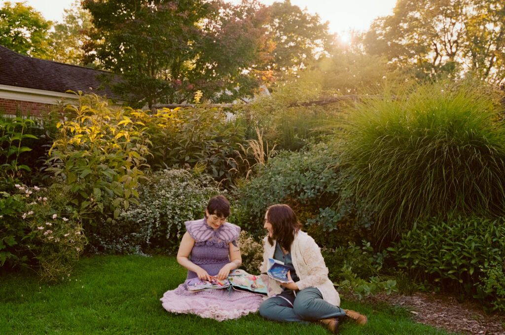 Newlywed couple sit amongst the lush greenery to admire each other's wedding gifts.