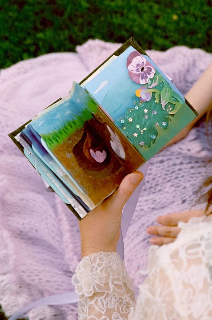 A detail photograph of a carousel book, showcasing cut paper scenes that have been painted and collaged. 