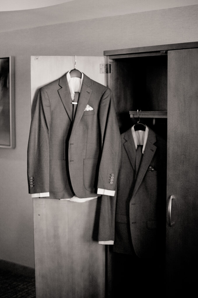 two men's wedding suits hanging in closet