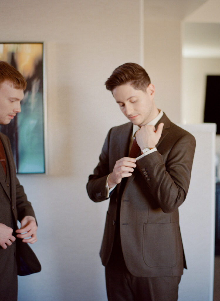 Queer couple smiling while getting dressed for wedding ceremony. Queer film wedding photography