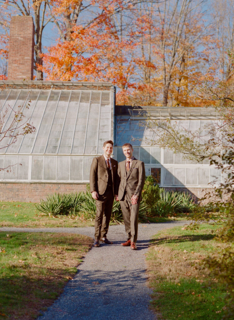 Queer couple on wedding day posing in front of the green house at Lyman Estate