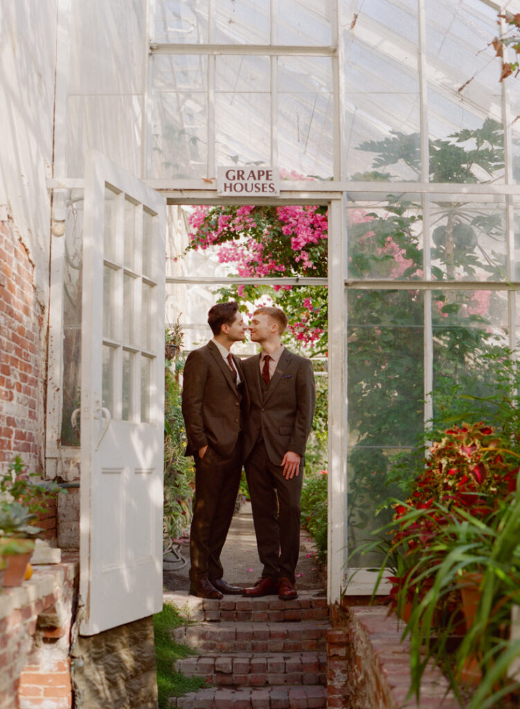 two queer men posing in a green house on their wedding day at The Lyman Estate