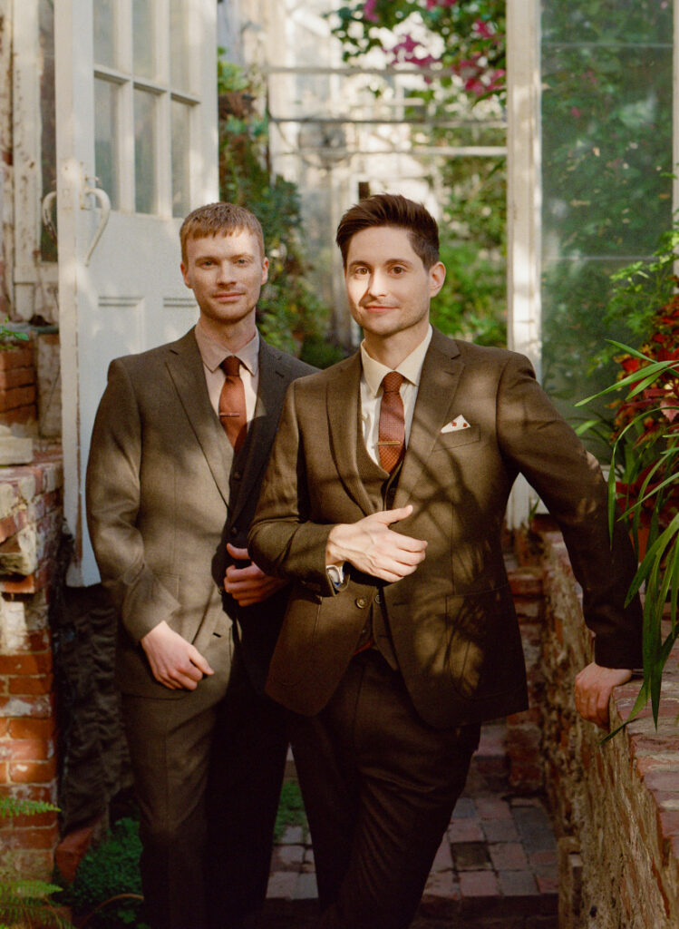 two queer men posing in a green house on their wedding day at The Lyman Estate