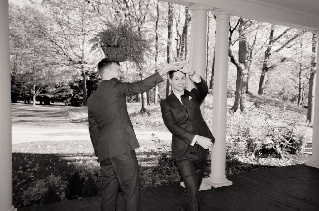 black and white photo of a queer man spinning his soon to be husband in a circle