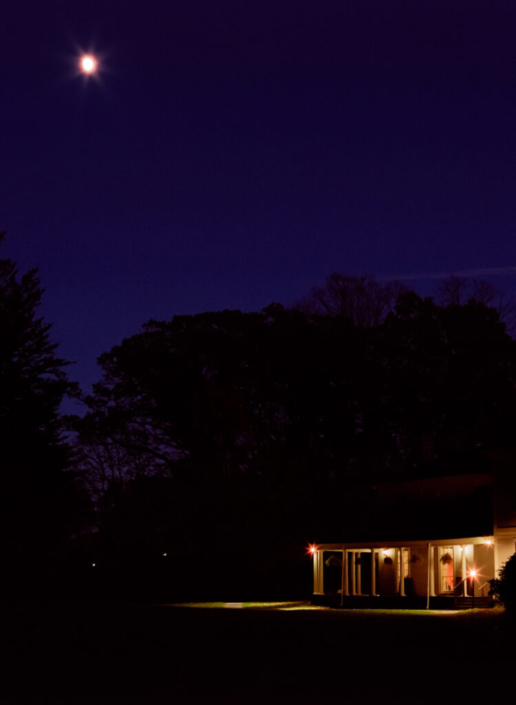 Lyman Estate light from within while the moon shines outside