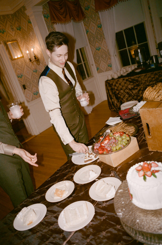 groom holding drink and looking at a piece of wedding cake