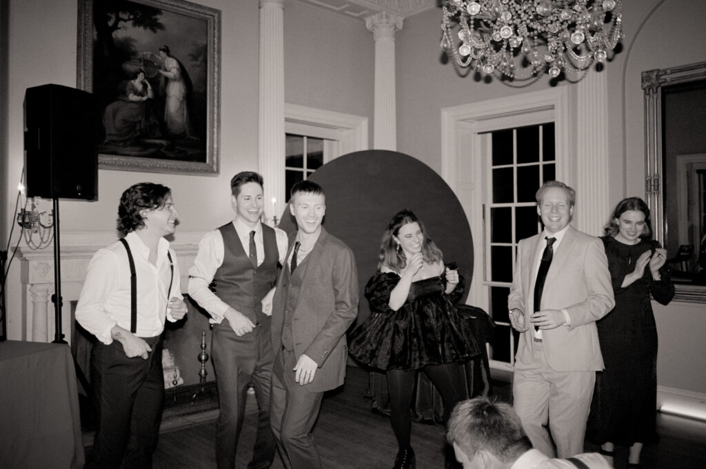 wedding guests and queer grooms smiling and enjoying wedding reception together