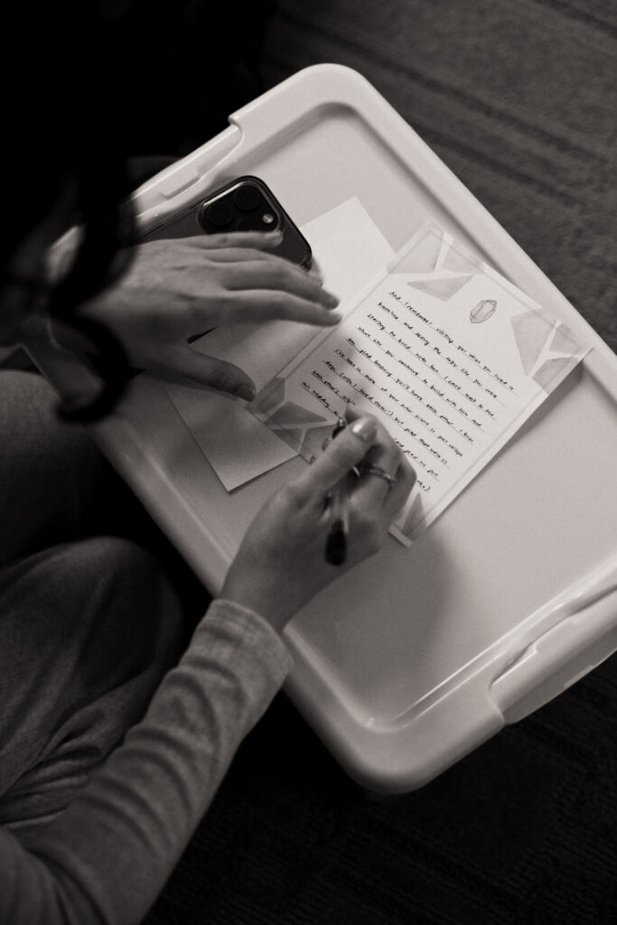 Black ad white photo of bridesmaid writing a heartfelt letter to the bride on her wedding day