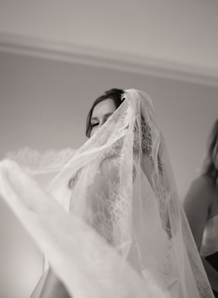 black and white photo of bride hiding her face behind her cathedral veil