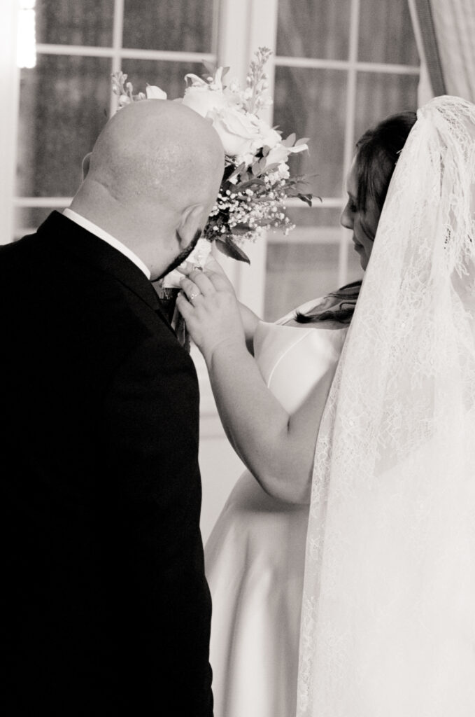 black and white photo of bride and groom looking at brides floral bouquet