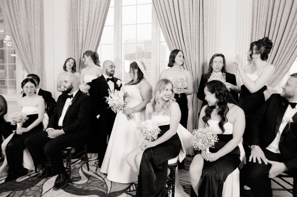 bridal party smiling and talking to one another in black and white photo