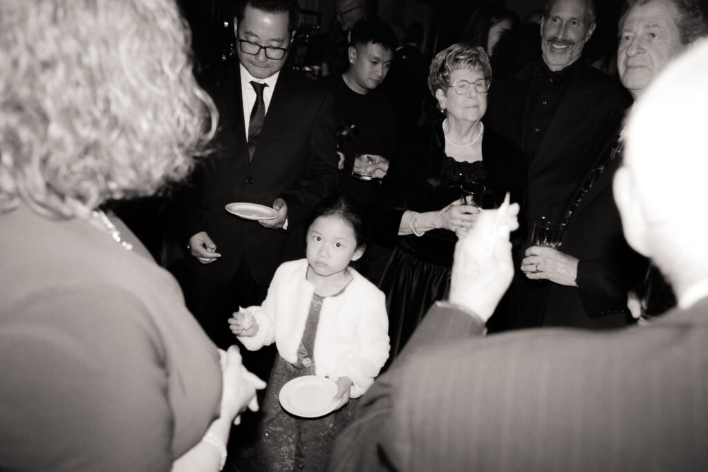 black and white photo of wedding guests talking and eating cake