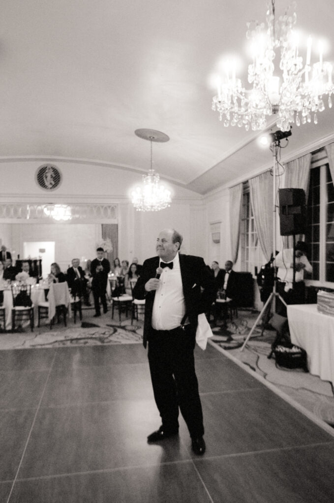 father doing a speech at wedding in black and white photo