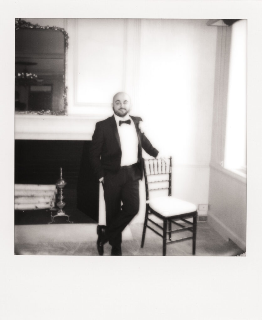 polaroid photo of groom posing next to chair