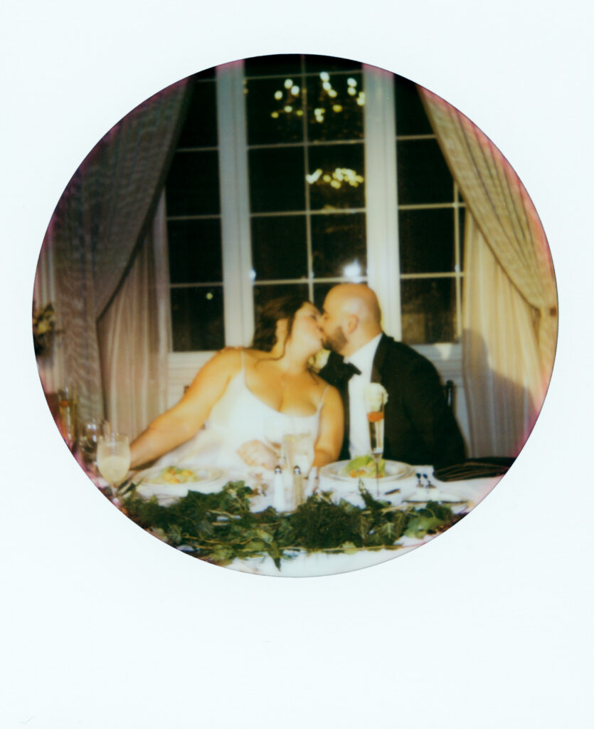 polaroid of bride and groom kissing at dinner table