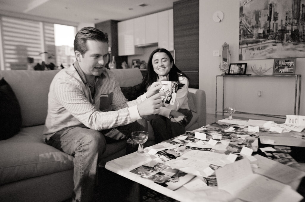 a man and woman sitting on a couch looking at a book at a engagement shoot on film 