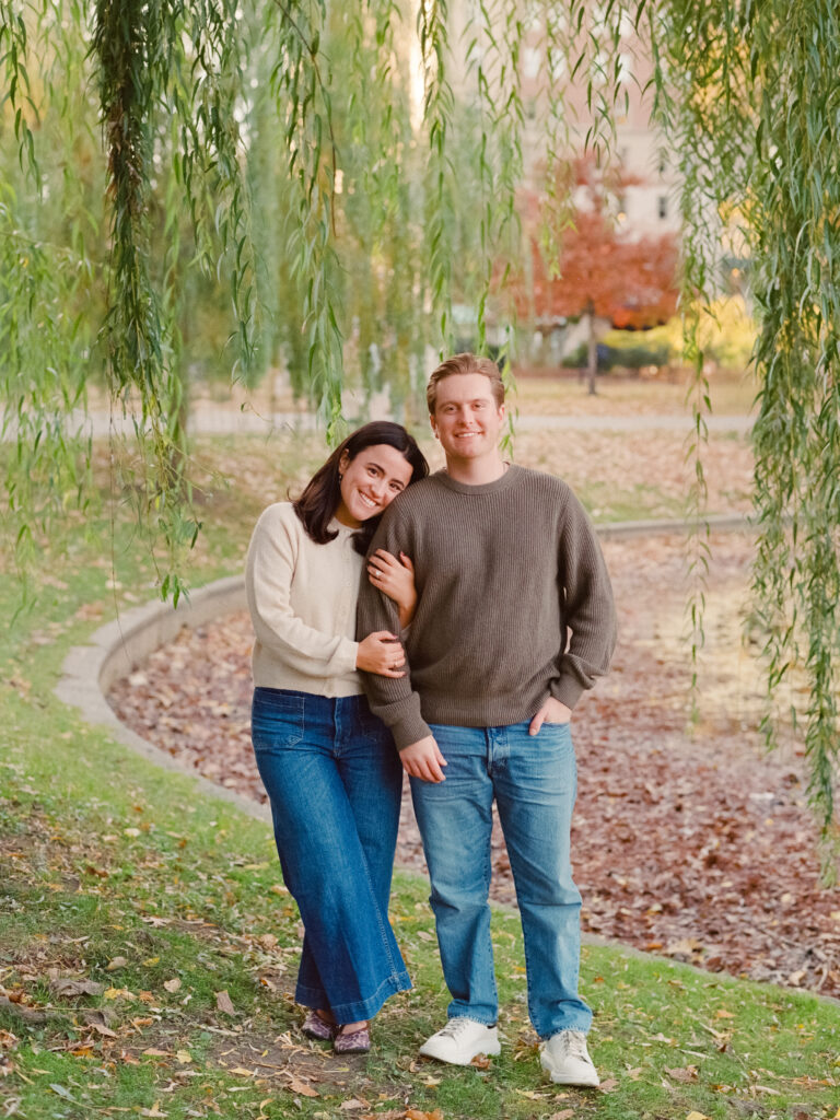 couple smiling under a tree during film engagement photos 