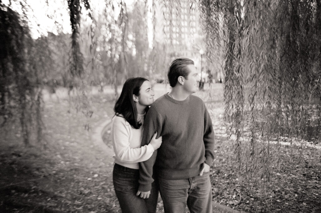 couple smiling under a tree during film engagement photos 