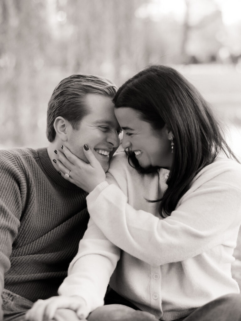couple smiling under a tree during film engagement photos 