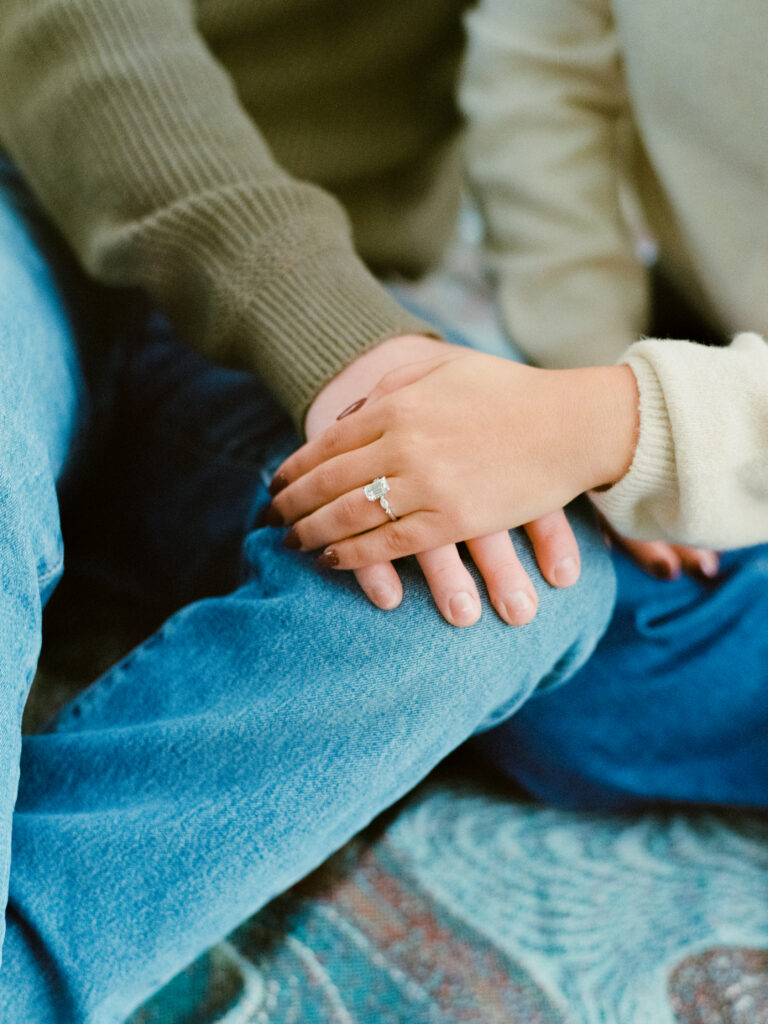 couple holding hands showing engagement ring 