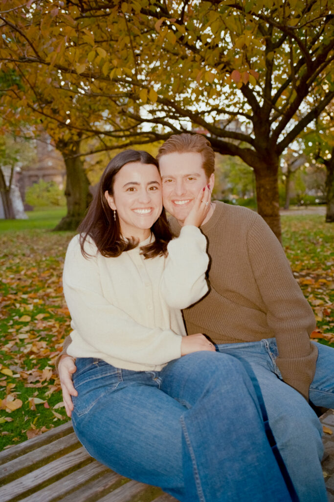 couple smiling under a tree during film engagement photos 
