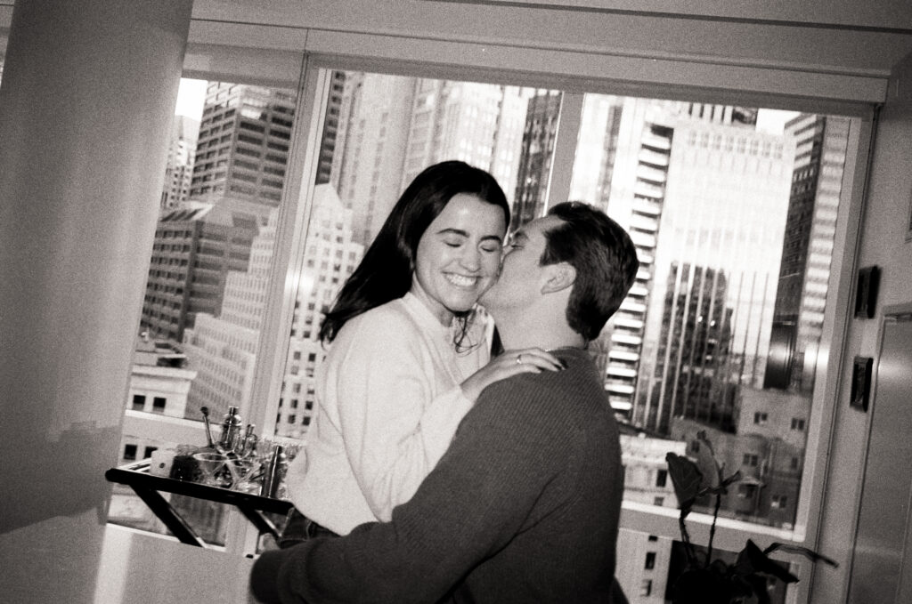 man kissing women on cheek while she smiles during film engagement photos 