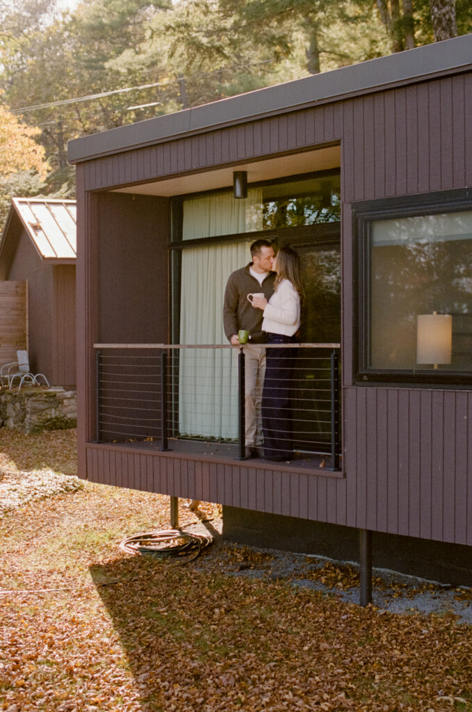 couple kissing on balcony holding coffee