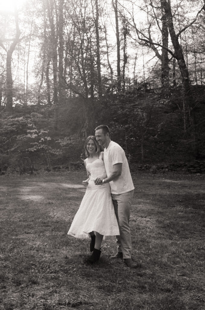 man spinning woman in white dress while smiling and giggling during film engagement photos